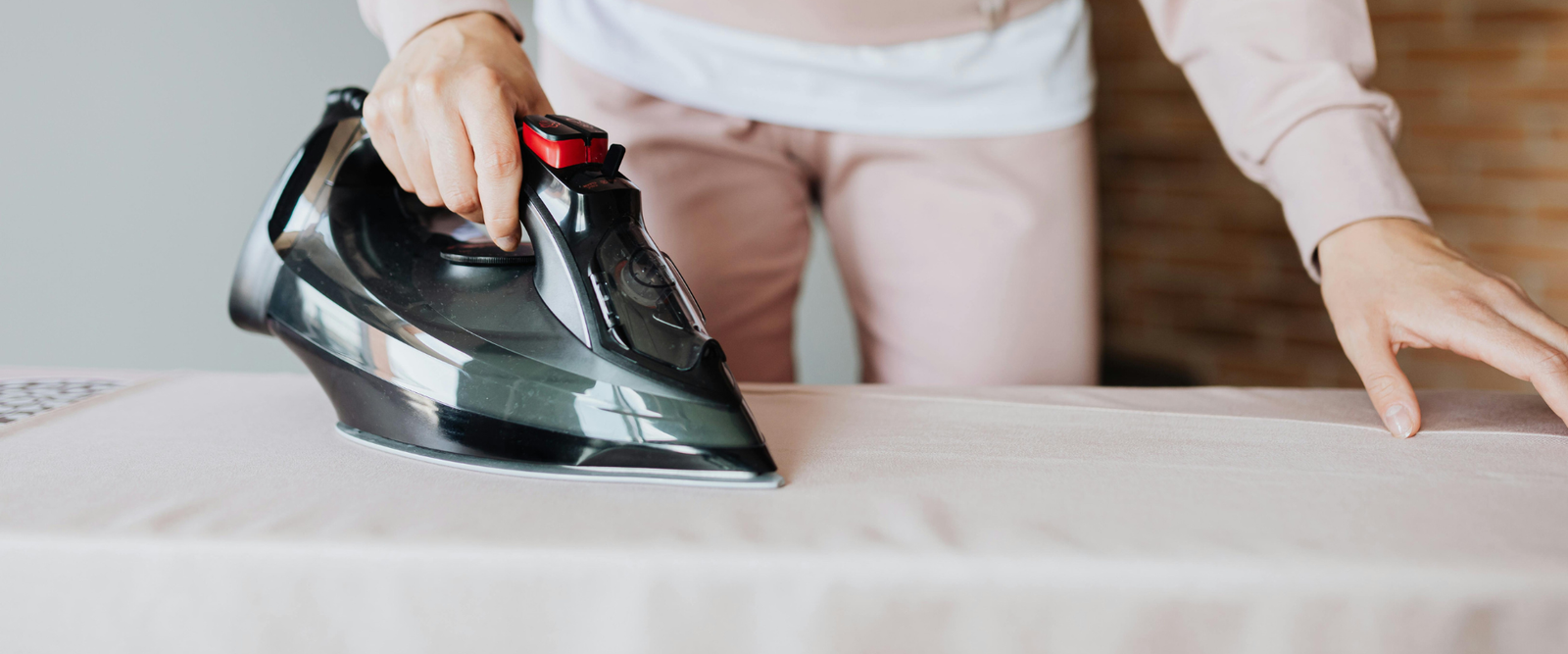 Thermoband Bügelband wird von Frau mit Bügeleisen am Vorhang angebracht, um ihn zu kürzen